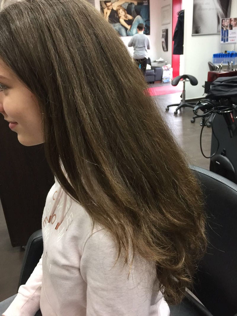 Langes braunes Haar mit sichtbar strapazierten Spitzen, Vorheraufnahme Langes, braunes Haar mit leicht unruhiger Struktur und sichtbar strapazierten Spitzen in einem Friseursalon.